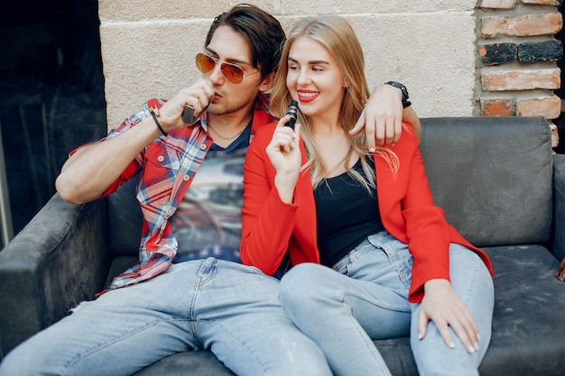 Stylish young couple with vape in a cafe