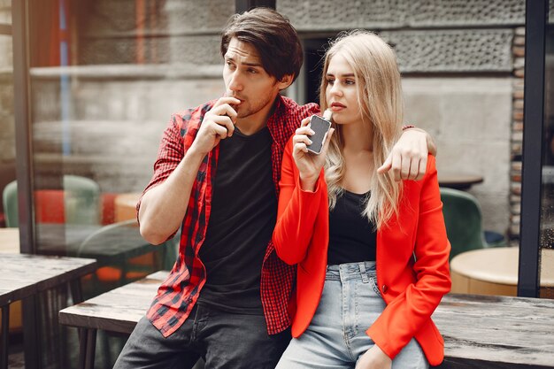 Stylish young couple with vape in a city 