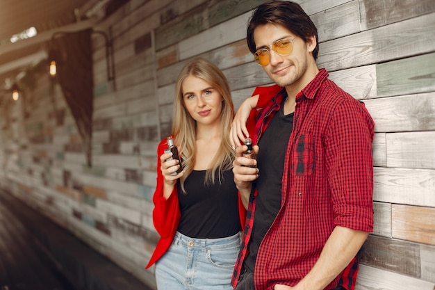 Stylish young couple with vape in a city 