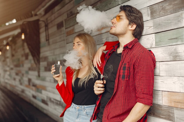 Stylish young couple with vape in a city 