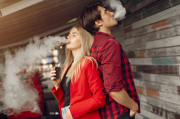 Stylish young couple with vape in a city 