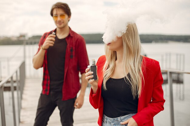 Stylish young couple with vape in a city 