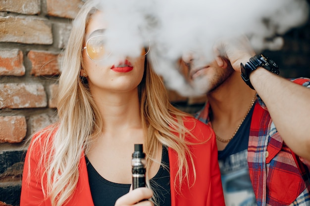 Foto gratuita giovani coppie alla moda con vape in una città