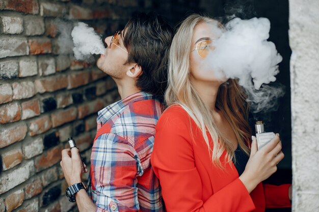 Stylish young couple with vape in a city