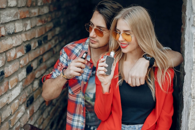 Stylish young couple with vape in a city