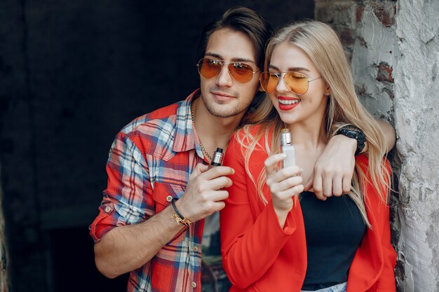 Stylish young couple with vape in a city