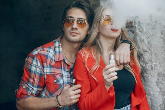 Free photo stylish young couple with vape in a city