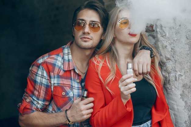 Giovani coppie alla moda con vape in una città