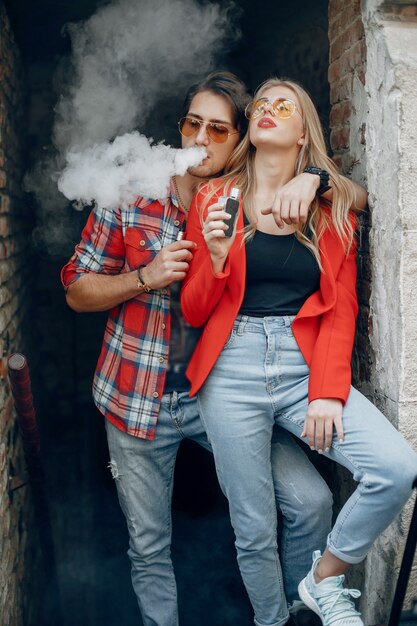 Stylish young couple with vape in a city