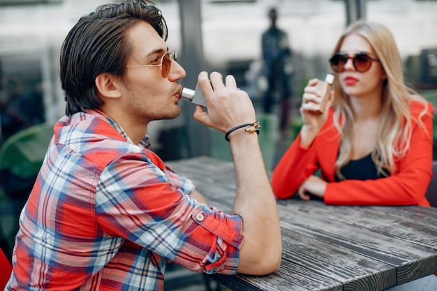 Stylish young couple with vape in a city