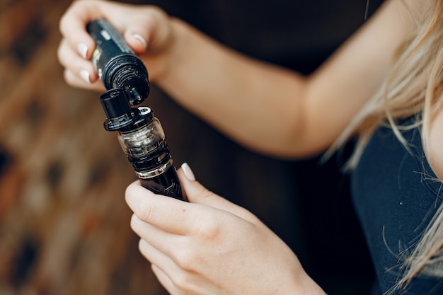 Free photo stylish young girl  in a city with vape