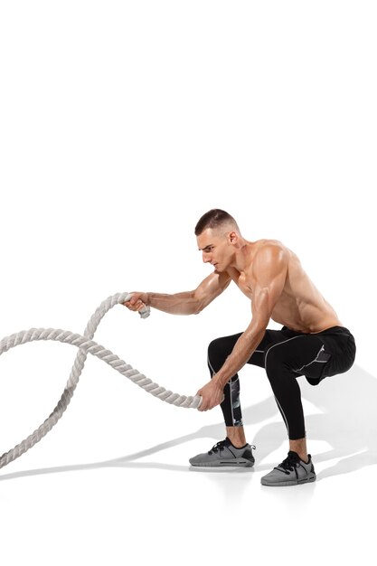 Stylish young male athlete practicing on white studio background, portrait with shadows. Sportive fit model in works out in motion and action.