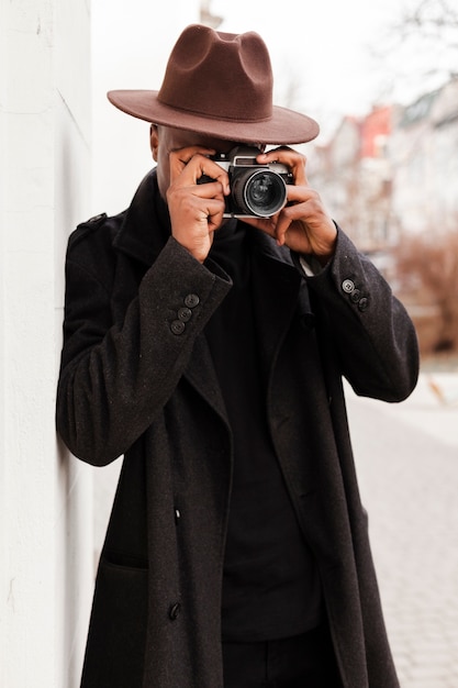 Free photo stylish young male with hat taking a picture