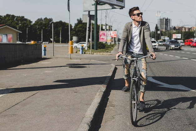 Стильный молодой человек, езда на велосипеде на улице