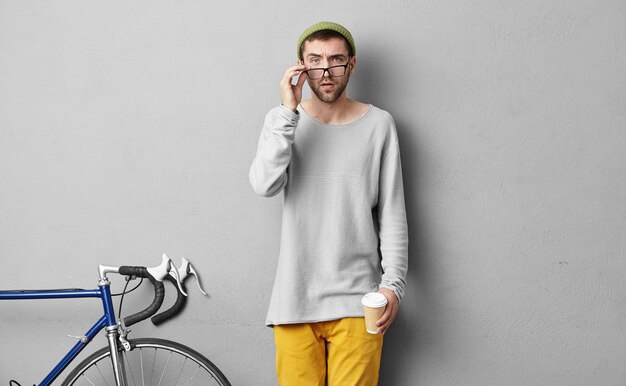 Stylish young man standing near bicycle