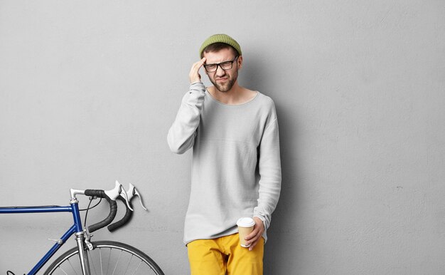 Stylish young man standing near bicycle