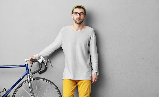 Stylish young man standing near bicycle