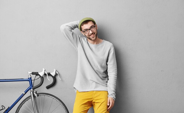 Stylish young man standing near bicycle