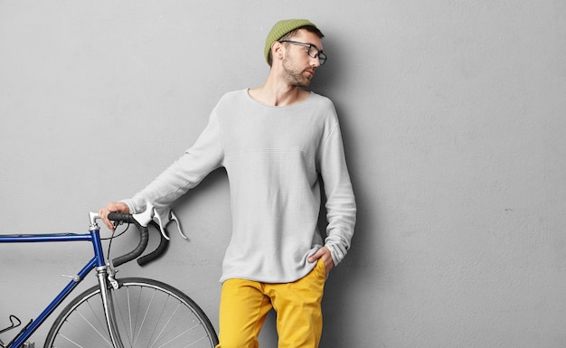 Stylish young man standing near bicycle