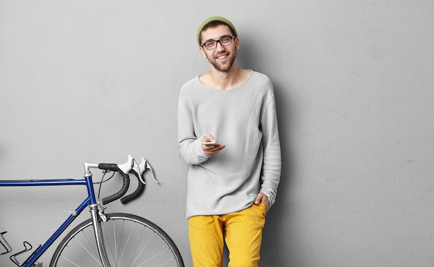 Foto gratuita elegante giovane uomo in piedi vicino alla bicicletta