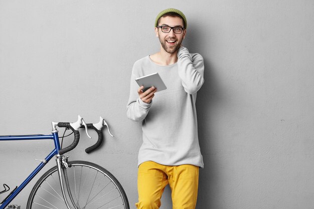 Stylish young man standing near bicycle