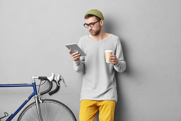 Elegante giovane uomo in piedi vicino alla bicicletta