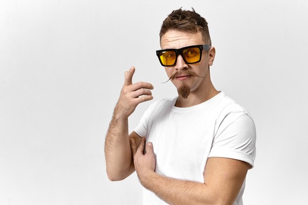 Стильный молодой человек в солнечных очках и белой футболке, скрывающей один глаз