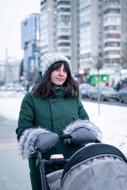 Stylish young mother for a walk with her baby in a baby carriage in winter