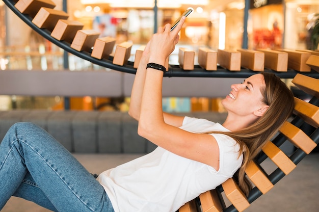 Free photo stylish young woman browsing mobile phone