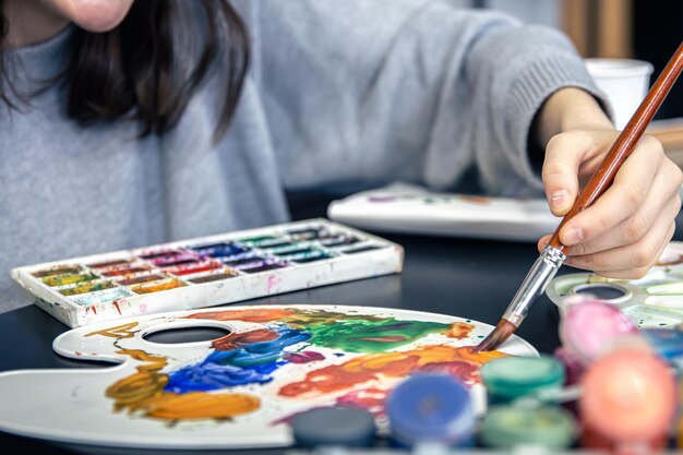 A stylish young woman draws with paints in the home interior