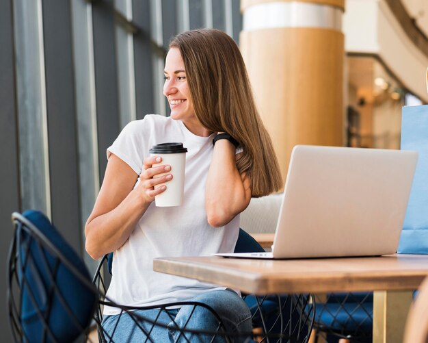 コーヒーカップを保持しているスタイリッシュな若い女性