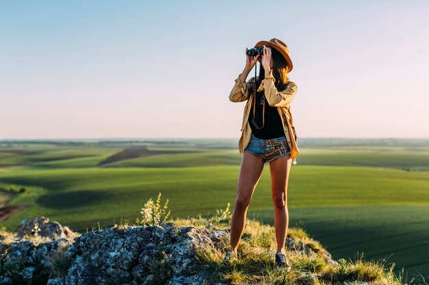 Stylish young woman looking through binoculars