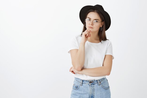 stylish young woman posing against white wall