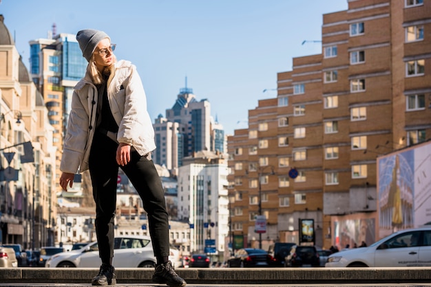 Free photo stylish young woman posing in front of city buildings