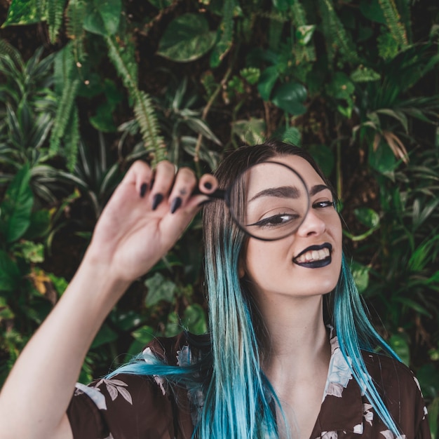 Stylish young woman showing eye through a magnifying glass