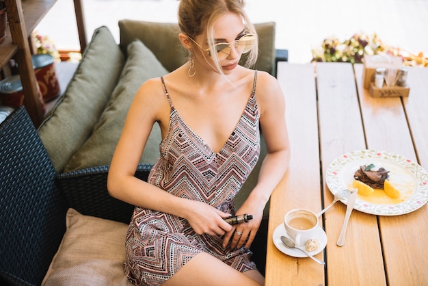 커피와 아침 식사와 카페에 앉아 세련 된 젊은 여자