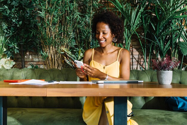 Стильная молодая женщина, сидя в ресторане с помощью смартфона