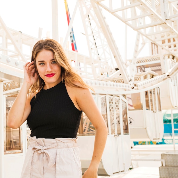 Stylish young woman standing in front of white ferris wheel