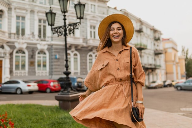 Stylish young woman traveling in Europe dressed in spring trendy dress, hat, bag and accessories