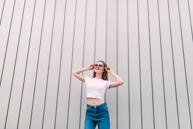 Stylish young woman white shirt posing on white striped wall