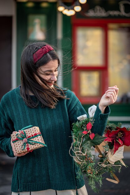 빨간색과 녹색 색상의 크리스마스 화환을 가진 세련된 젊은 여성