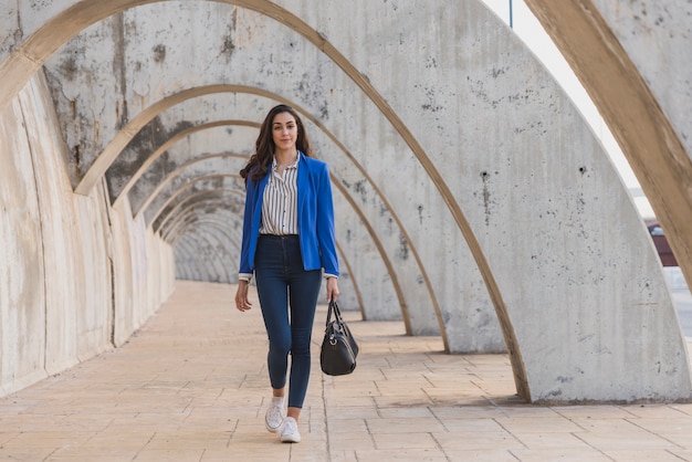 Elegante giovane donna con la borsa a piedi