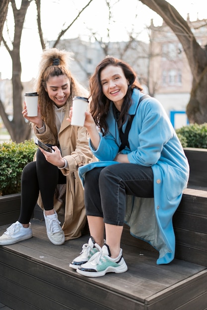 Giovani donne alla moda che godono insieme del caffè