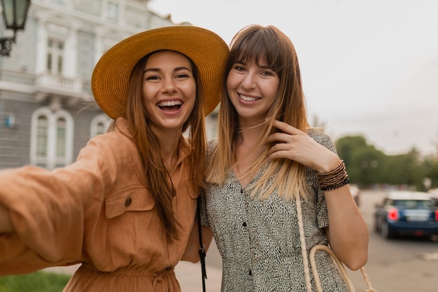 Stylish young women traveling together in Europe dressed in spring trendy dresses and accessories