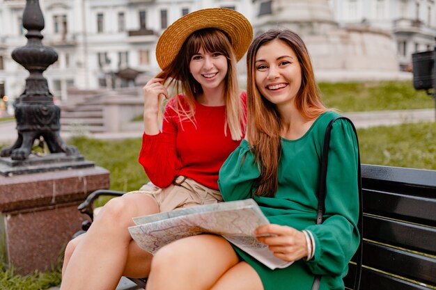 Stylish young women traveling together in Europe dressed in spring trendy outfit and accessories