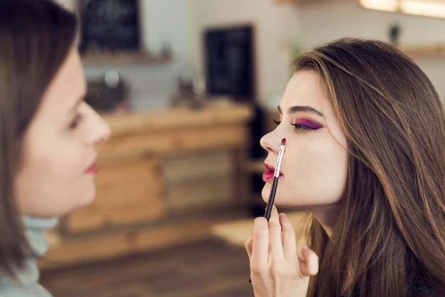 Free photo stylist applying bright eyeshadow on model