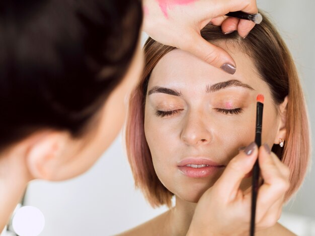 Stylist applying eyeshadow on model