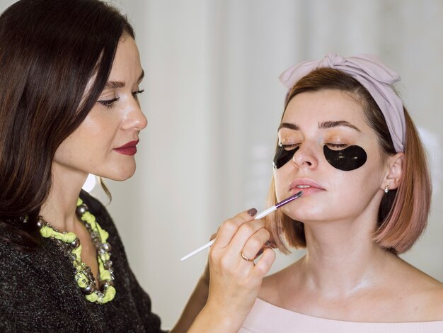 Stylist applying lipstick on natural woman