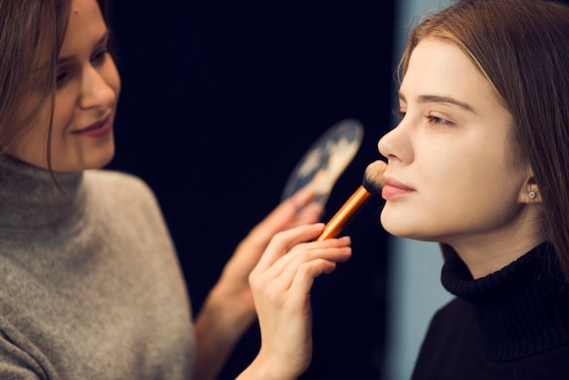 Stylist applying powder on young model