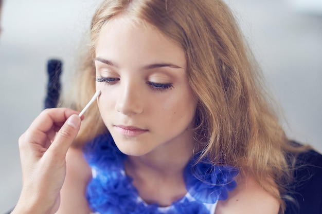 Free photo stylist doing the make-up for a beautiful little girl model. close-up image.